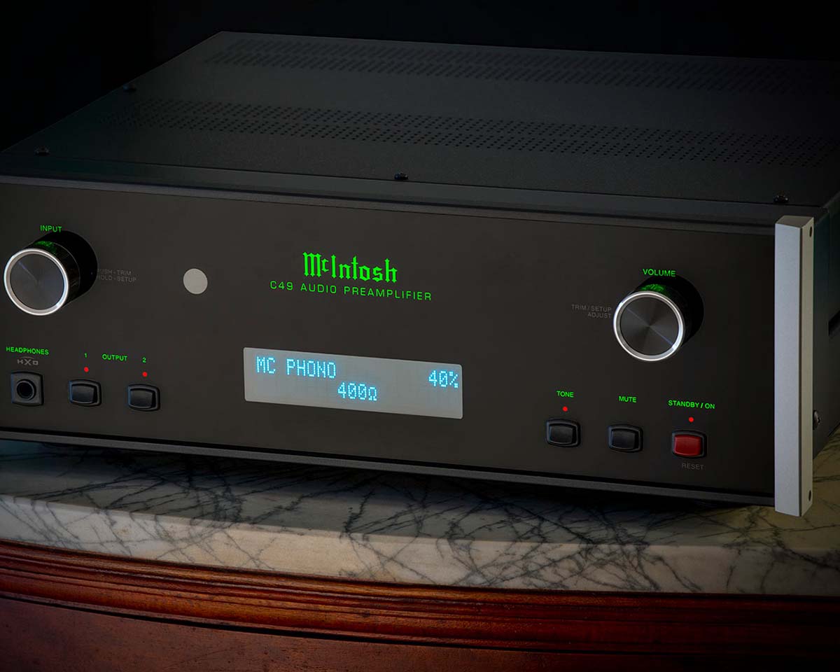 Black McIntosh C49 audio preamplifier on a marble surface, featuring green logo, silver knobs, and blue LED display, conveying a sleek, high-end design.