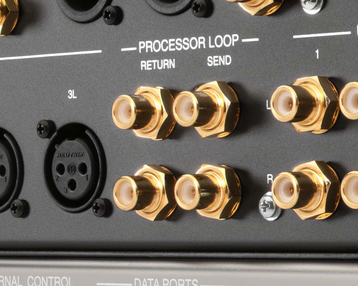 Close-up of a black audio processor panel featuring gold connectors labeled "Processor Loop," "Return," and "Send," alongside XLR audio ports.
