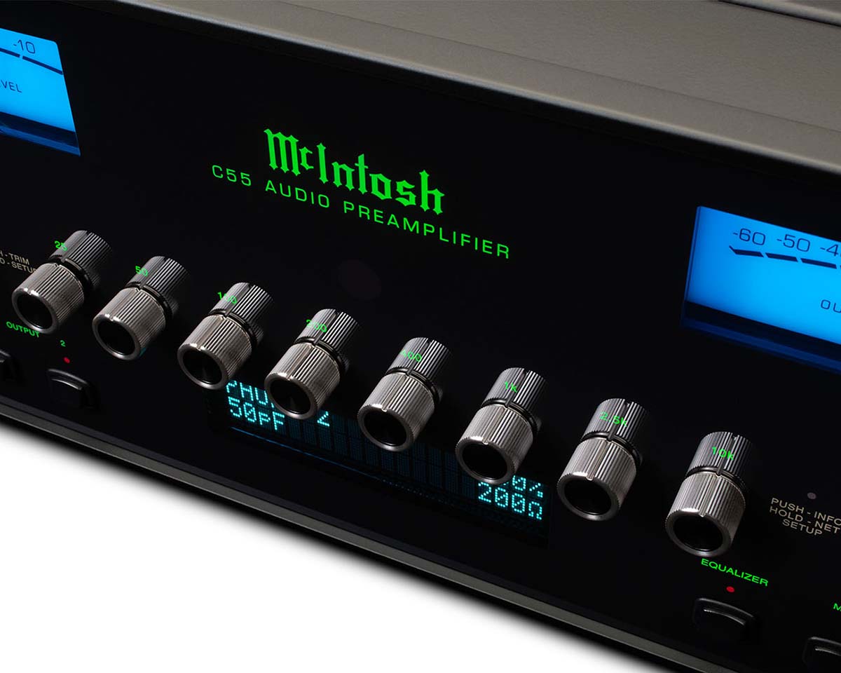 Close-up of a McIntosh C55 audio preamplifier. Features seven silver control knobs, green text, and glowing blue meters, conveying a high-tech feel.