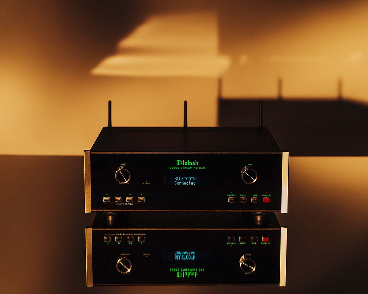 A black audio receiver with glowing green display reading "Bluetooth Connected," set against a warm, golden, softly lit background, casting reflections.