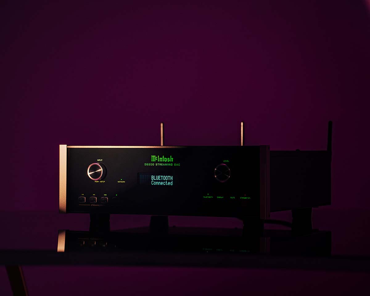 High-end audio equipment in dim purple lighting. The display reads "Bluetooth Connected." Sleek design with metal knobs, conveying a modern, sophisticated feel.
