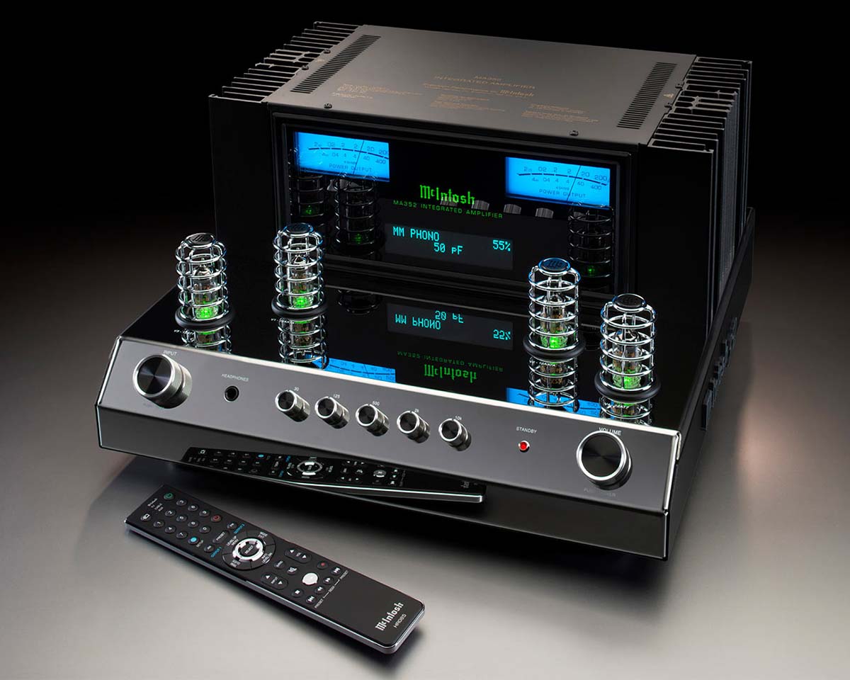 High-end audio equipment with glowing tubes, sleek black design, and a remote control on a reflective surface, conveying luxury and sophistication.