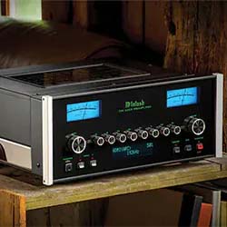 Vintage stereo amplifier with blue-lit dials and knobs on a wooden surface. The setting is rustic, suggesting a classic, nostalgic atmosphere.