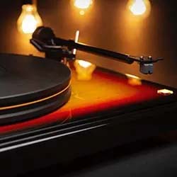 Vinyl record player with a glowing amber wood finish, set against a warm background of hanging vintage bulbs, creating a nostalgic ambiance.