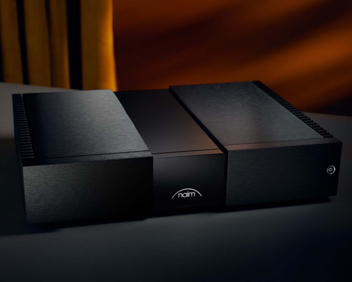 A sleek black amplifier with the "naim" logo centered, set against a dark background with warm lighting, conveying a modern and sophisticated tone.