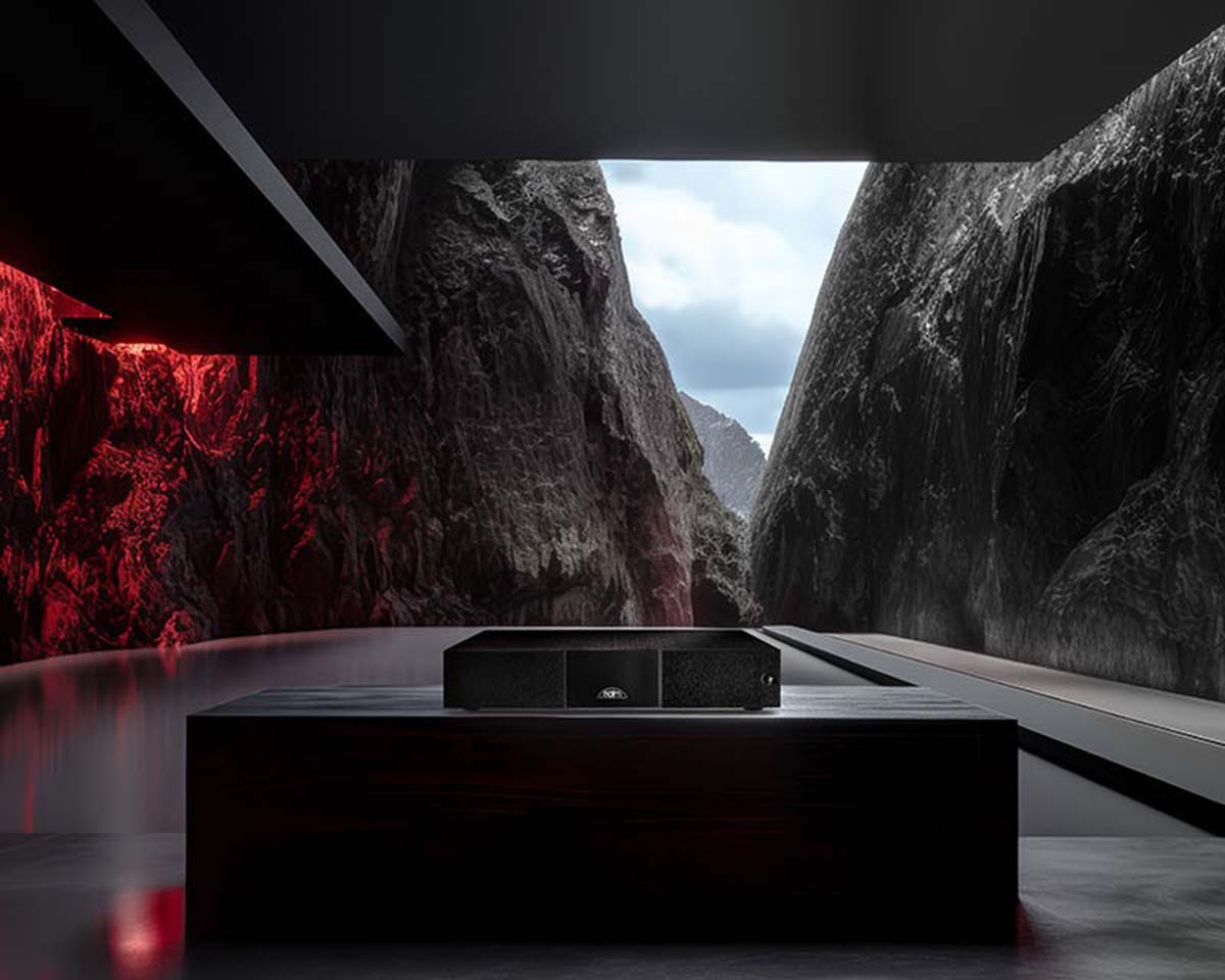 Futuristic interior with sleek black furniture and a central device, set against a dramatic rocky landscape. Red lighting adds a mysterious ambiance.