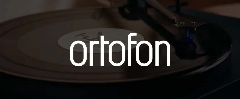A vinyl record spinning on a turntable, with a focus on the Ortofon stylus in action. The word "ortofon" is prominently overlaid in white text.