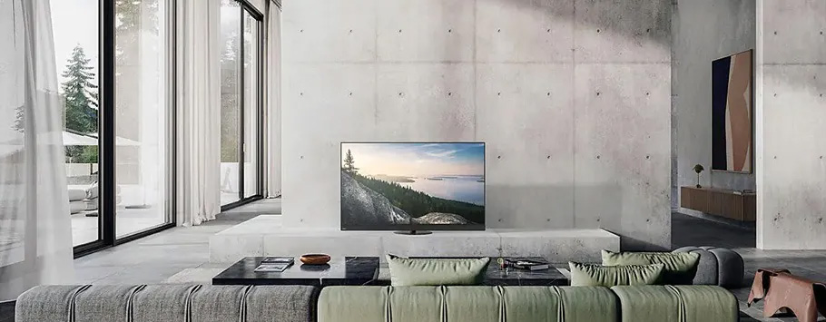 Spacious modern living room with high ceilings, large windows, and a minimalist design. Features a grey couch, TV, and abstract art, creating a serene atmosphere.