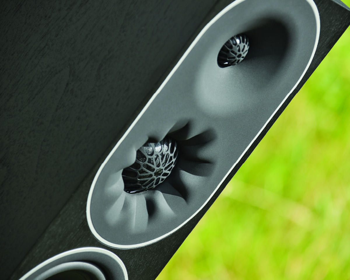 Close-up of a modern speaker with a unique, textured cone design. The gray tones contrast with a blurred green background, creating a sleek, innovative look.