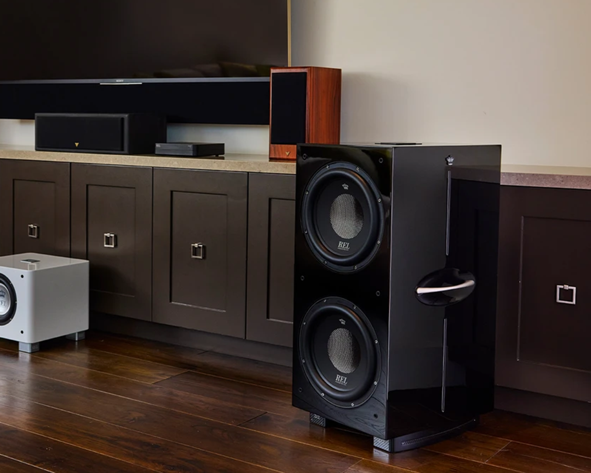 Stylish living room with large black speakers, sleek brown cabinets, and wooden flooring. A modern audio setup creates a sophisticated ambiance.