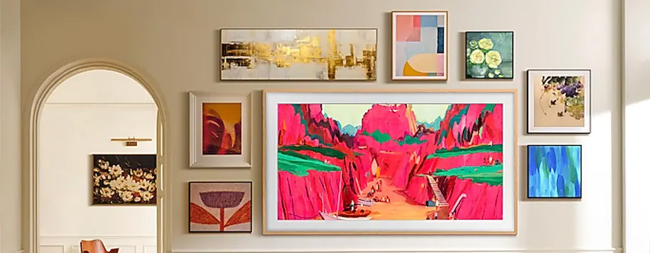 Gallery wall with diverse artwork, including a large, vibrant pink canyon painting centered among smaller abstract and nature pieces. Warm, inviting atmosphere.