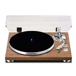 A wooden turntable with a clear dust cover, black platter, and silver tonearm sits on a flat surface, conveying a classic, retro vibe.