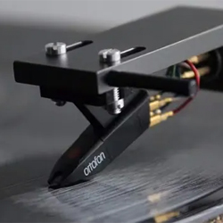 Close-up of a turntable needle touching a vinyl record. The tonearm is sleek and modern, with wires exposed, creating a nostalgic yet high-tech vibe.