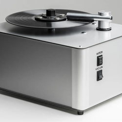 A sleek, modern vinyl record cleaning machine with a black record on top. It features control switches labeled "Motor" and "Vacuum" on the side.