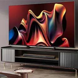 A large TV with a vibrant abstract display sits on a modern black and gray entertainment unit. The room has a minimalist and contemporary design.