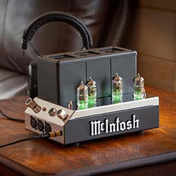 A retro McIntosh headphone amplifier with glowing vacuum tubes sits on a wooden table, evoking vintage audio elegance and sophistication.