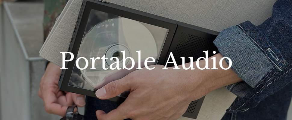 A person holds a portable CD player against their hip. They are wearing a denim jacket. Overlaid text reads "Portable Audio." The tone is nostalgic.