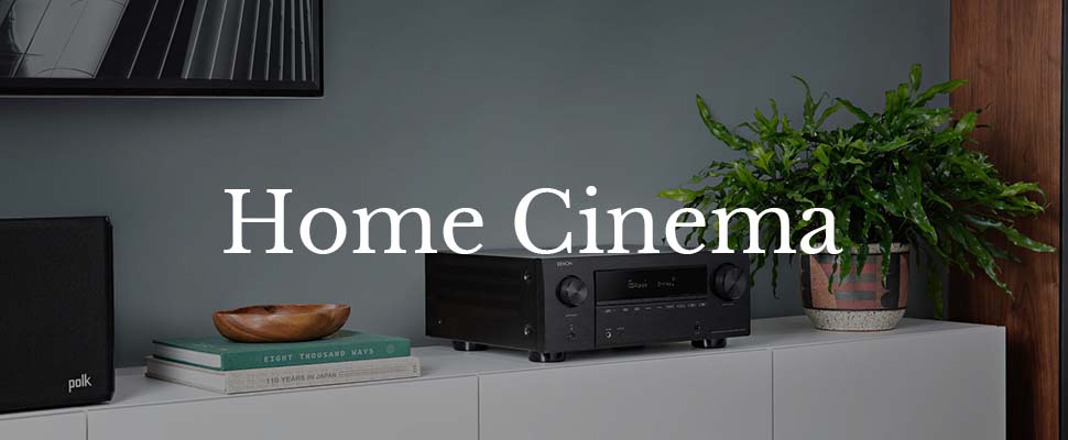 Modern home cinema setup on a white cabinet, featuring a black audio receiver, a speaker, and green plant. Text overlay reads "Home Cinema."