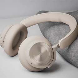 Beige over-ear headphones with a sleek design rest on a soft gray fabric background. The scene conveys a sense of modernity and comfort.