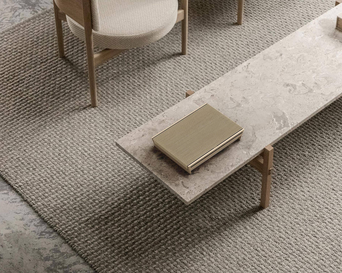 Minimalist living room with a textured gray rug, wooden furniture, and a long stone coffee table. A sleek book with a striped cover adds elegance.