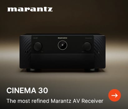 Marantz promotional banner showcasing the Cinema 30 audio-video receiver with the headline "CINEMA 30" and subtext "The most refined Marantz AV Receiver". The banner features a centered, front-facing view of the premium black home cinema receiver sitting against a smooth, solid warm brown background. The product's symmetrical facade highlights two large control knobs flanking a small, circular porthole digital display screen in the center. The white Marantz brand logo is positioned at the top left corner, and an orange circular action button with a white right-pointing arrow sits in the bottom right corner.