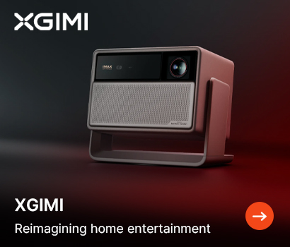 XGIMI promotional banner for home entertainment. The image features a close-up of a modern XGIMI smart projector with an integrated swivel stand, resting on a dark surface under dramatic red and blue atmospheric studio lighting. The projector's front face shows a gold lens and a mesh speaker grille. The white XGIMI logo is placed at the top left, with the slogan "XGIMI. Reimagining home entertainment" at the bottom left, next to a circular orange action button with a white arrow pointing right.
