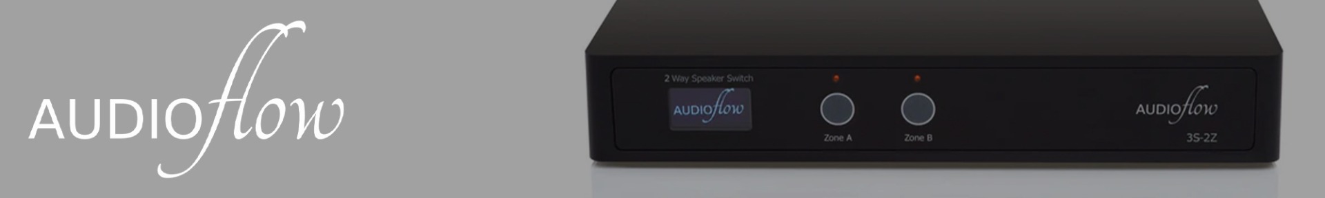 Sleek black Audioflow speaker switch with illuminated labels "Zone A" and "Zone B" on a gray backdrop. The logo appears in elegant white font.