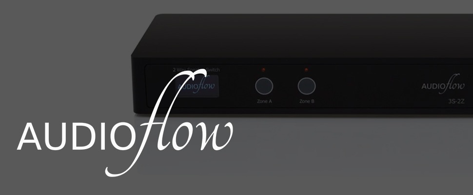 Sleek black Audioflow speaker switch with illuminated labels "Zone A" and "Zone B" on a gray backdrop. The logo appears in elegant white font.
