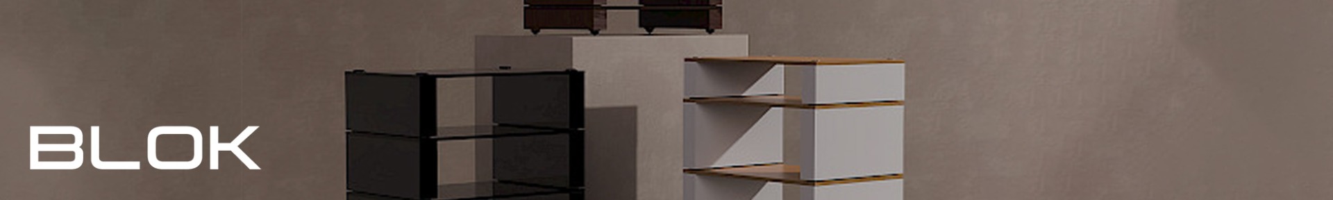 Minimalist room with geometric storage units in black and white on platforms, set against a grey wall. The word "BLOK" is visible.