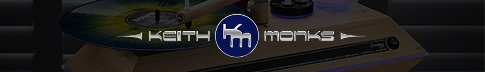 A vinyl record is spinning on a wooden turntable, partially visible with the logo 'Keith Monks' in metallic font overlaying the image.