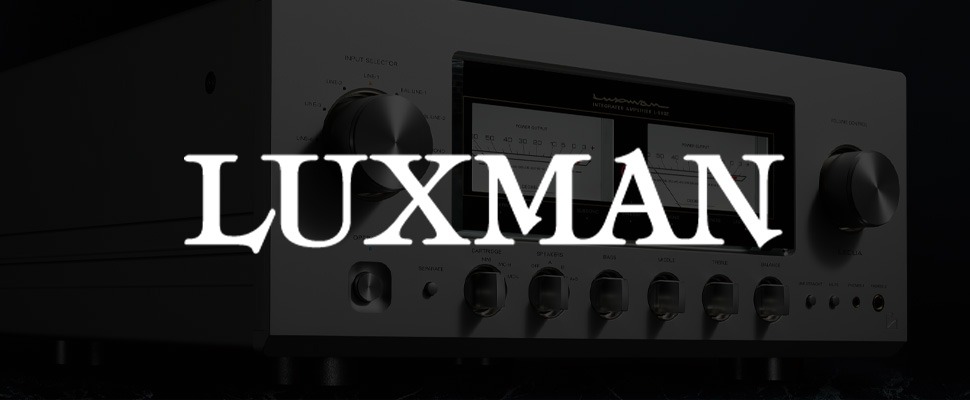 Close-up of a Luxman amplifier with two large dials and illuminated power output meters. The sleek design and dim lighting convey modern sophistication.