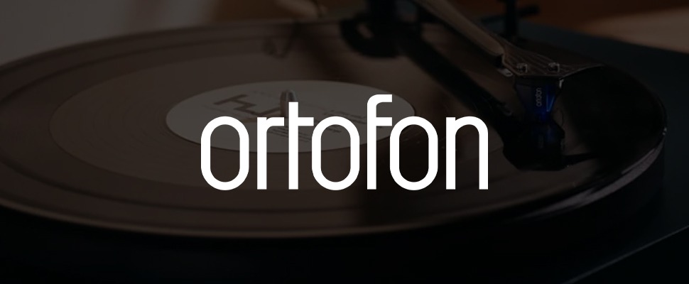 Close-up of a vinyl record playing on a turntable with "ortofon" branding. The needle is on the record, conveying nostalgia and music appreciation.