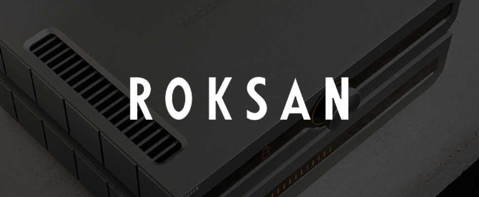 Close-up of a sleek, modern audio amplifier with a metallic surface and air vents, next to the stylized white text 'Roksan' on a grey background