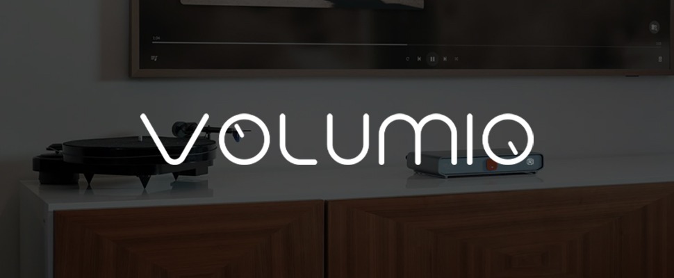 Modern audio setup with a turntable on a sleek white surface and a compact audio device beside it, resting on a wooden cabinet. The word "Volumio" is displayed.