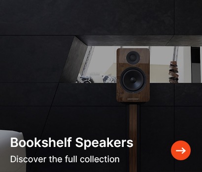 A sleek room features a bookshelf speaker on a stand against a black wall. Text reads "Bookshelf Speakers. Discover the full collection."