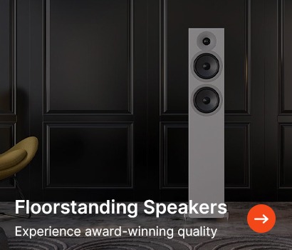 Elegant white floorstanding speaker with two woofers against a black panelled wall, next to a green chair. Text: "Floorstanding Speakers. Experience award-winning quality."
