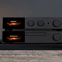 A sleek black audio system with glowing orange lights and multiple knobs, sitting on a wooden surface. The background is dimly lit, creating a modern feel.