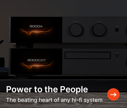 Alt text: Stack of hi-fi audio components with glowing displays reading "9000A" and "9000CDT" on a wooden surface. Text reads, "Power to the People: The beating heart of any hi-fi system" with an arrow icon.