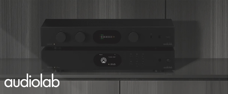 A sleek audiolab audio system is shown on a white marble and wood shelf. Nearby, audiolab-branded boxes rest under soft, natural light, conveying elegance.