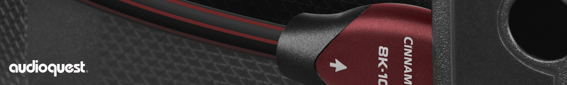 Close-up of an AudioQuest Cinnamon 8K HDMI cable, showing its red and black connector against a textured surface. 