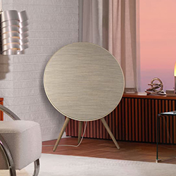 Stylish modern living room with a large circular speaker on wooden legs against a white brick wall. Soft lighting creates a cozy and elegant ambiance.