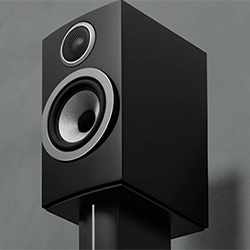 A sleek black speaker on a stand set against a gray background. It features two circular drivers, conveying a modern and high-quality audio design.