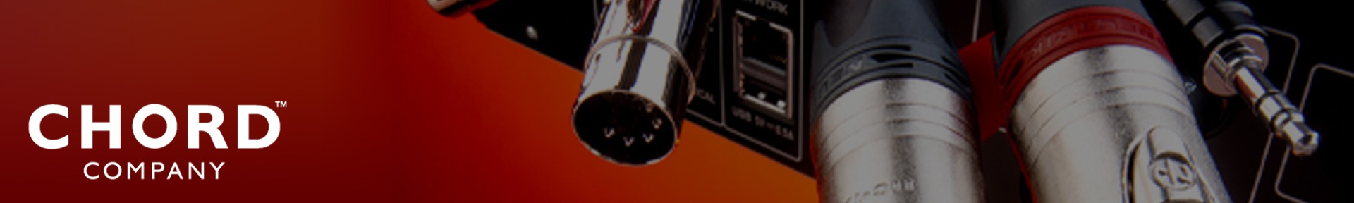 Close-up of audio cables and connectors against a gradient red background. The cables have metallic finishes with visible ports. Text: "Chord Company."
