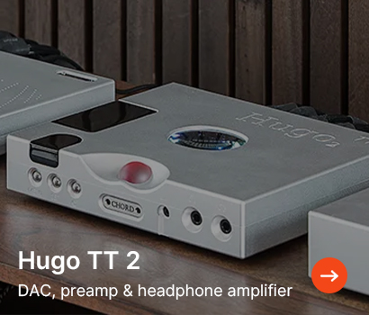Silver Hugo TT 2 audio device with circular display, multiple dials, and ports on a wooden surface. Text reads: "DAC, preamp & headphone amplifier."