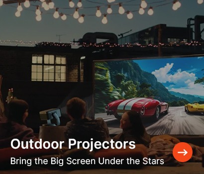 Outdoor movie night on a rooftop with string lights. A group watches cars race on a projector screen. Text: "Outdoor Projectors. Bring the Big Screen Under the Stars."
