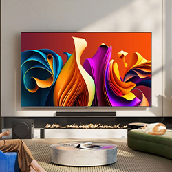A modern living room features a vibrant abstract art display on a large TV, with colorful swirls. A cat sleeps on a green couch, creating a cozy atmosphere.