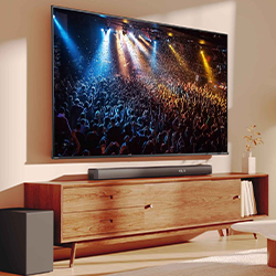A flat-screen TV on a wooden stand shows a vibrant concert scene with colorful stage lights. A sleek soundbar and bookshelf add a modern touch to the room.