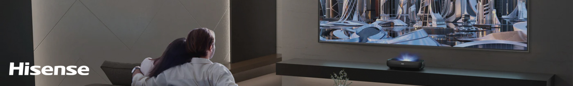 A couple watches a futuristic cityscape on a large wall-mounted TV in a dark, modern living room. "Hisense" is written in white in the corner.