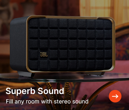 A black JBL speaker with gold trim sits on a table in a cosy, warmly lit room. Text reads, "Superb Sound: Fill any room with stereo sound."