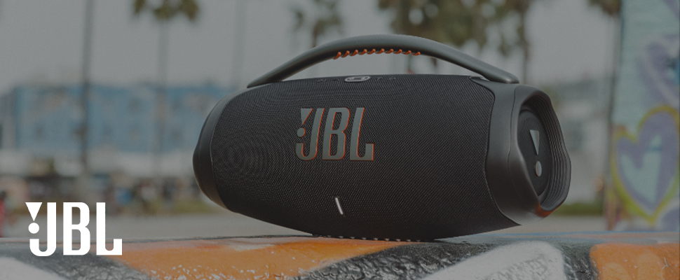Close-up of a black JBL portable speaker with the JBL logo prominently displayed. The background is a blurred graffiti wall, creating an urban vibe.